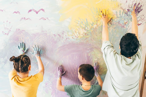 children painting with their hands on a wall