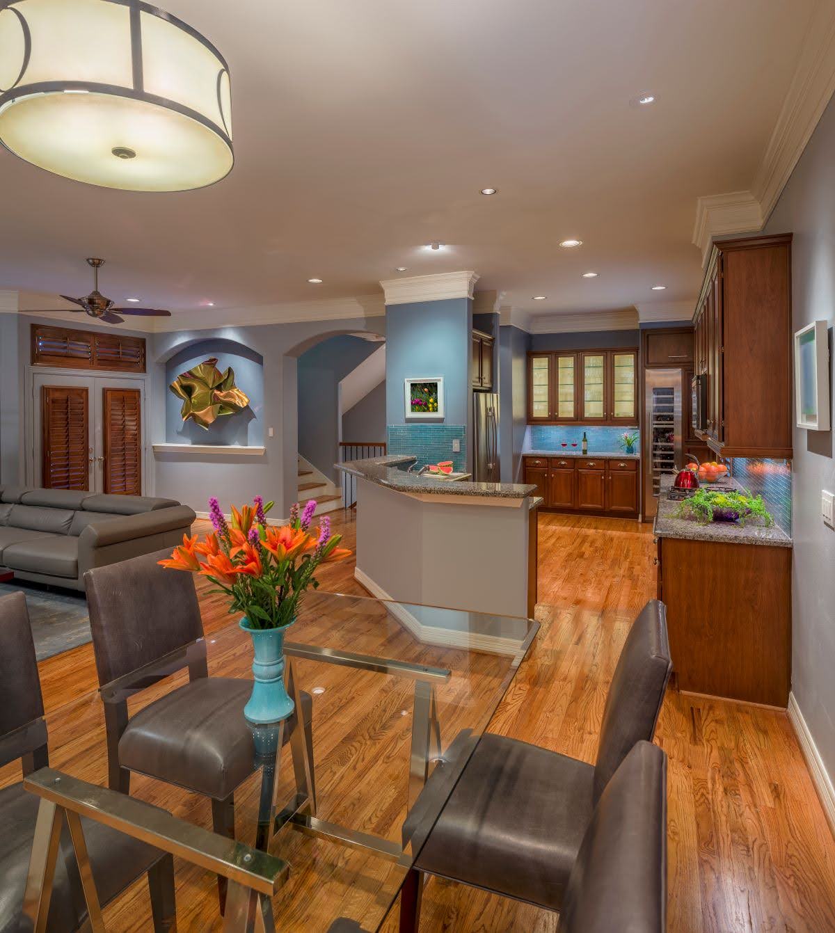 Open-concept living space with kitchen, dining area, and living room featuring warm tones, hardwood floors, and modern furnishings.